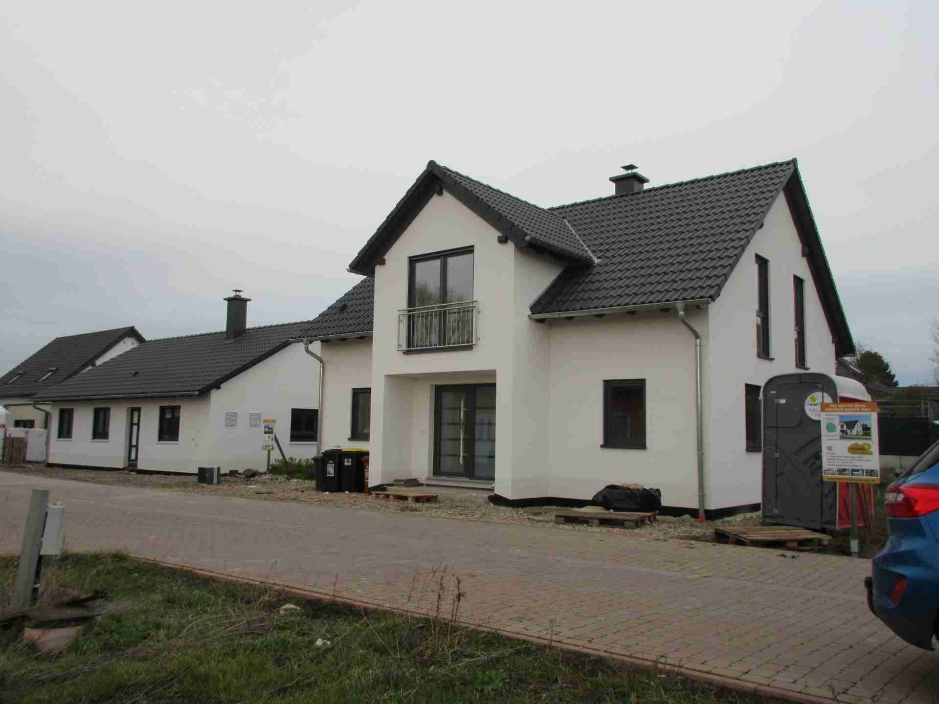 Ein Einfamilienhaus in weiß gehalten mit grauen Fensterrahmen